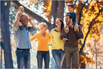 Drei Generationen beim Spaziergang durch den sonnigen Herbstwald